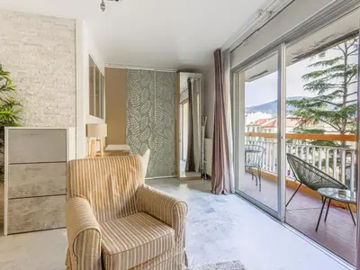 a living room with a chair and a balcony at Apartment Les Arènes de Cimiez-1 by Interhome in Nice