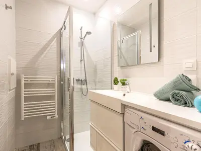 a white bathroom with a shower and a washing machine at Apartment Les Arènes de Cimiez-1 by Interhome in Nice