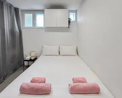 a bedroom with a large bed with two pink pillows at Studio Centre Ville proche TRAM & Port, Wifi Gratuit in Nice