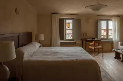 a bedroom with a table and chairs and windows at Hôtel du Couvent, a Luxury Collection Hotel, Nice in Nice