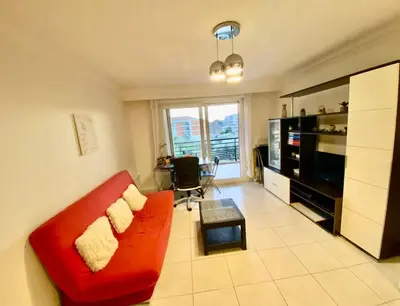 a living room with a red couch and a television at Nice Ouest St Isidore- 2P au calme in Nice