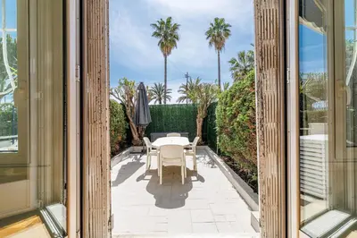a patio with a table and chairs and palm trees at Promenade des Anglais 2 Bdr Large Terrace in Nice
