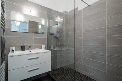 a bathroom with a sink and a glass shower at Promenade des Anglais - 2 chambres - Jardin in Nice