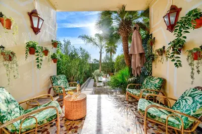 a patio with chairs and tables and palm trees at Promenade des Anglais - 2 chambres - Jardin in Nice