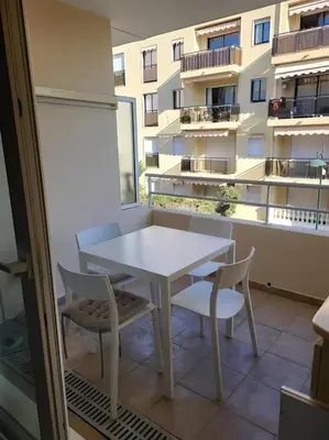 a white table and chairs on a balcony with a building at Appartement idéalement situé proche bord de mer in Beaulieu-sur-Mer