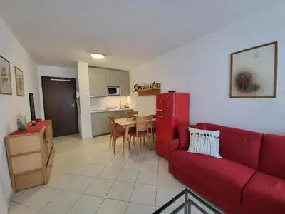 a living room with a red couch and a kitchen at Appartement idéalement situé proche bord de mer in Beaulieu-sur-Mer