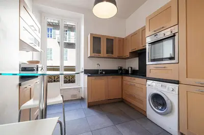 a kitchen with wooden cabinets and a washer and dryer at MY CASA - ETATS UNIS 892 - Spacious flat on Sea front w AC in Nice