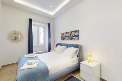 a white bedroom with a blue bed and a mirror at Suite Stars FSHH in Nice