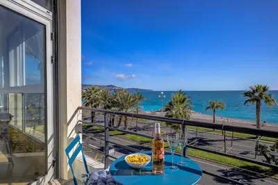 a table with a drink on a balcony with a view of the beach at Maison Bianchi - 187 Promenade des Anglais - Sea view in Nice