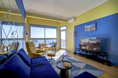 a living room with a blue couch and a tv at Maison Bianchi - 187 Promenade des Anglais - Sea view in Nice