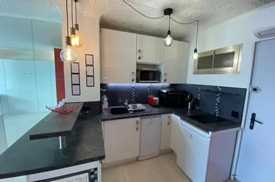 a kitchen with white cabinets and black counter tops at 06BH - Beautiful seafront studio in Saint-Laurent-du-Var