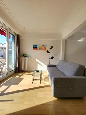 a living room with a couch and a large window at #TheCosyStudio06 Meyerbeer Promenade Negresco in Nice