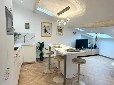 a kitchen with a table and stools in a room at Elegant mansardé-place du pin in Nice