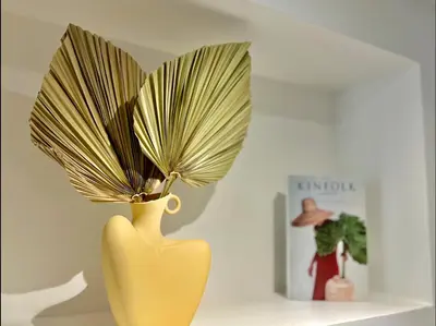 a yellow vase with a plant in it next to a book at LIBERATION CENTER - PRIVATE Balcony - 24&7 RECEPTION - LUGGAGE STORAGE in Nice