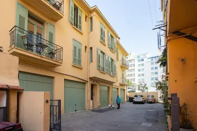 a person walking a dog in front of a building at L46 2P Port, 2min du Cap et 5 du port/ CLIM & WIFI in Nice