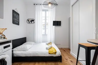 a small white bedroom with a bed and a kitchen at Charming City Center Studio 108 in Nice