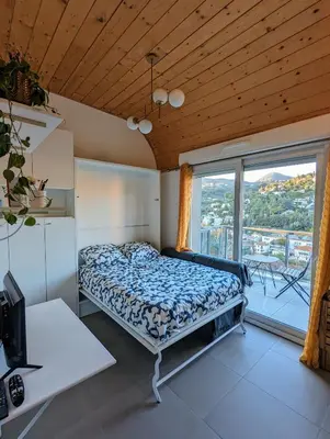 a bedroom with a bed and a large window at Studio calme avec vue dégagée in Nice
