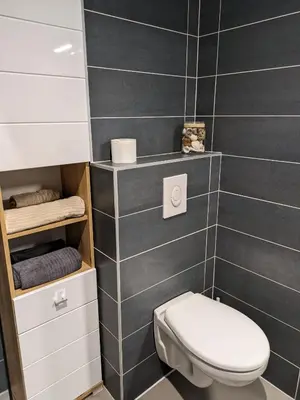 a bathroom with a toilet and a black tiled wall at Studio calme avec vue dégagée in Nice