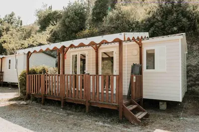 a wooden cabin with a fence and trees at Camping VAL FLEURI ATC Cagnes-Sur-Mer in Cagnes-sur-Mer