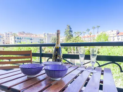 a wooden table with three bowls and a bottle of wine at Apartment Le Victor Hugo by Interhome in Nice