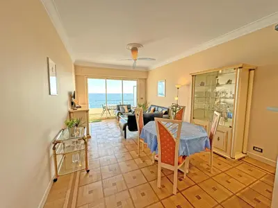 a living room with a table and a view of the ocean at Cosy Sea Front Apartment Nice France in Nice