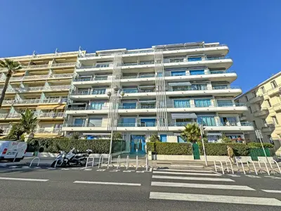 a large white building with chairs in front of it at Cosy Sea Front Apartment Nice France in Nice