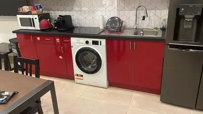 a kitchen with red cabinets and a washing machine at Grand loft à deux pas de la mer n1 in Nice