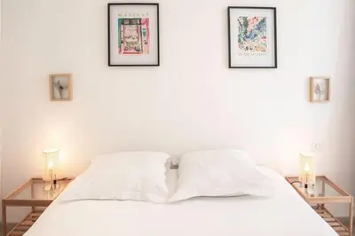 a bedroom with a white bed with three pictures on the wall at #21 2 Bdr balconies 10 mins walk to sea 5mins to tram in Nice