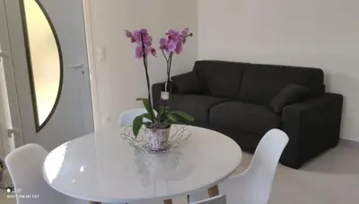 a white table with a vase with purple flowers on it at 2p bas de Villa avec Jacuzzi privatif proche de Nice in Saint-Laurent-du-Var