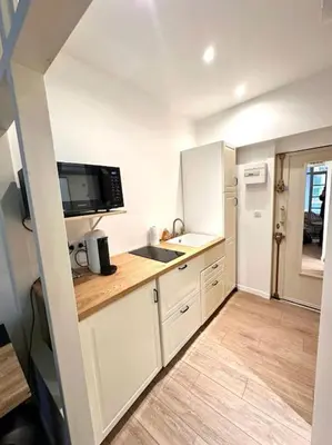 a kitchen with white cabinets and a sink and a refrigerator at Rue Droite - Studio cosy au coeur du Vieux-Nice in Nice