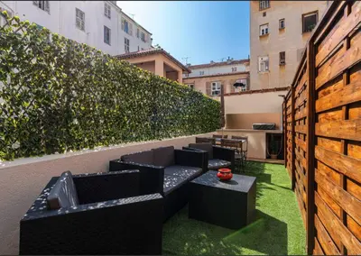 a rooftop patio with black furniture and green grass at Loft place Masséna avec terrasse in Nice