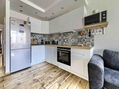 a kitchen with white appliances and a wooden floor at 1 min to beach bedroom flat with 2 AC and parking in summer in Nice