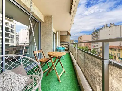 a balcony with a swing and a table and chairs at 1 min to beach bedroom flat with 2 AC and parking in summer in Nice