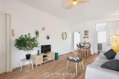 a white living room with a couch and a tv at Studio Californie FSHH in Nice