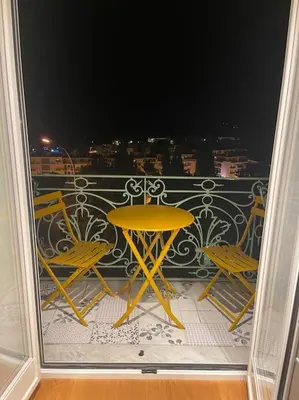 a balcony with a yellow table and two chairs at 5 mn du centre de Beaulieu. in Beaulieu-sur-Mer