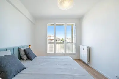 a white bedroom with a bed and a window at Appartement à 100m de la plage, climatisé in Cagnes-sur-Mer