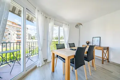 a dining room with a table and chairs and a balcony at Confortable 2 pièces 54 m2 proche de la mer in Nice