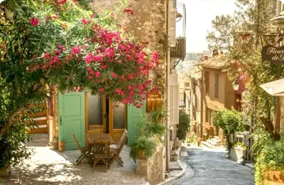 an alley with pink flowers and a table and chairs at Sea View Apartment - Private Parking, Swimming Pool, Air Conditioning in Cagnes-sur-Mer