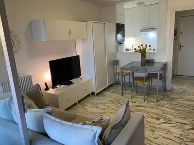 a living room with a couch and a kitchen with a table at Sea View Apartment - Private Parking, Swimming Pool, Air Conditioning in Cagnes-sur-Mer