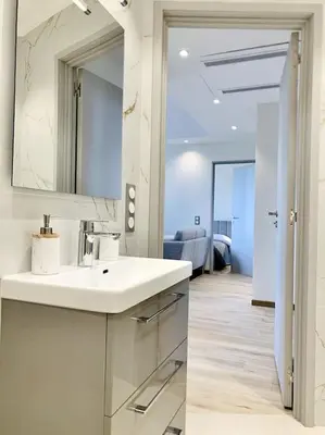 a white bathroom with a sink and a mirror at Bright, newly renovated apartment in Nice