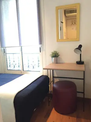 a bedroom with a bed and a table and a mirror at Hôtel du Petit Louvre in Nice