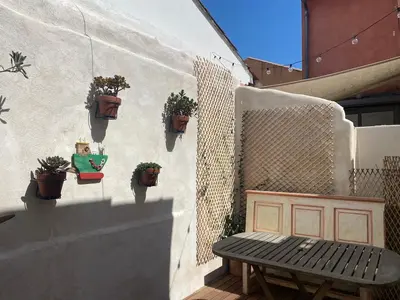 a patio with a bench and potted plants on a wall at Magnifique maison de pecheur face à la mer in Cagnes-sur-Mer