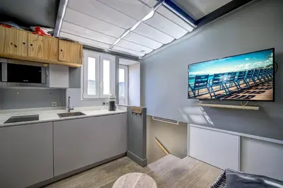 a kitchen with white cabinets and a tv on the wall at Maison Bianchi - Jean Médecin in Nice