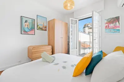 a white bedroom with a large bed and a window at Terrasse des Oliviers in Nice