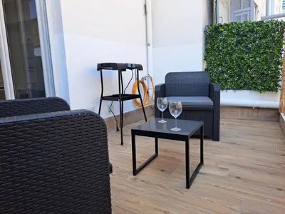 two chairs and a table with wine glasses on it at Studio coin nuit terrasse à 5 minutes de la plage N1 in Saint-Laurent-du-Var