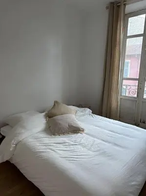 a white bed with two pillows and a window at Cosy Nice appartement in Nice