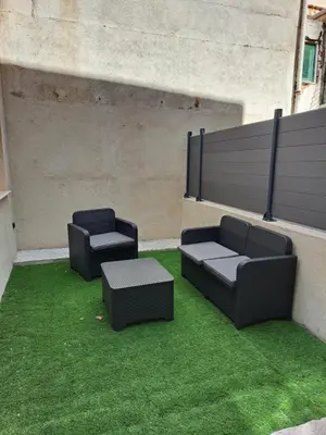 two black chairs andools on a patio with grass at Appartement 3 pièces à 5 minutes de la plage N7 in Saint-Laurent-du-Var
