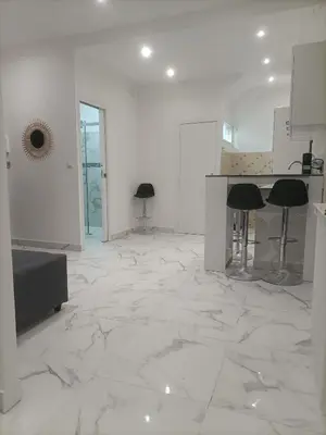 a large white room with marble floors and stools at Appartement confortable a proximite de la mer. in Nice