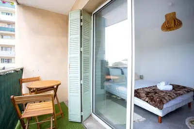 a room with a balcony with a bed and a table at 4 pièces 8 personnes proche aéroport,tramway in Nice