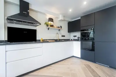 a kitchen with white cabinets and black appliances at Villa fleurie in Cagnes-sur-Mer